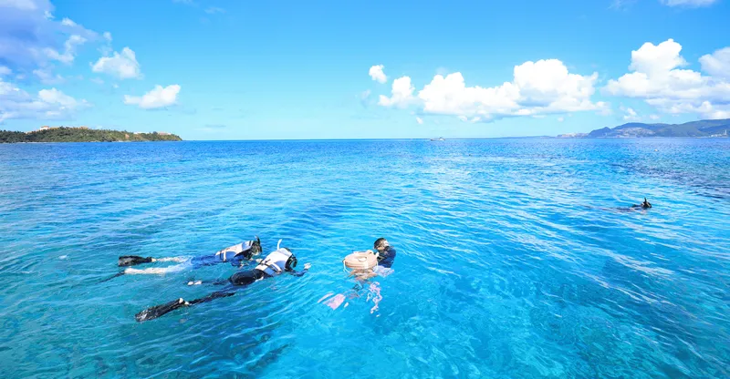 Snorkelers swimming over a coral reef with tropical fish on a Kerama Islands okinawa snorkeling day trip from Naha